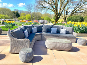 Outdoor patio furniture set with gray cushions on a sunny day.