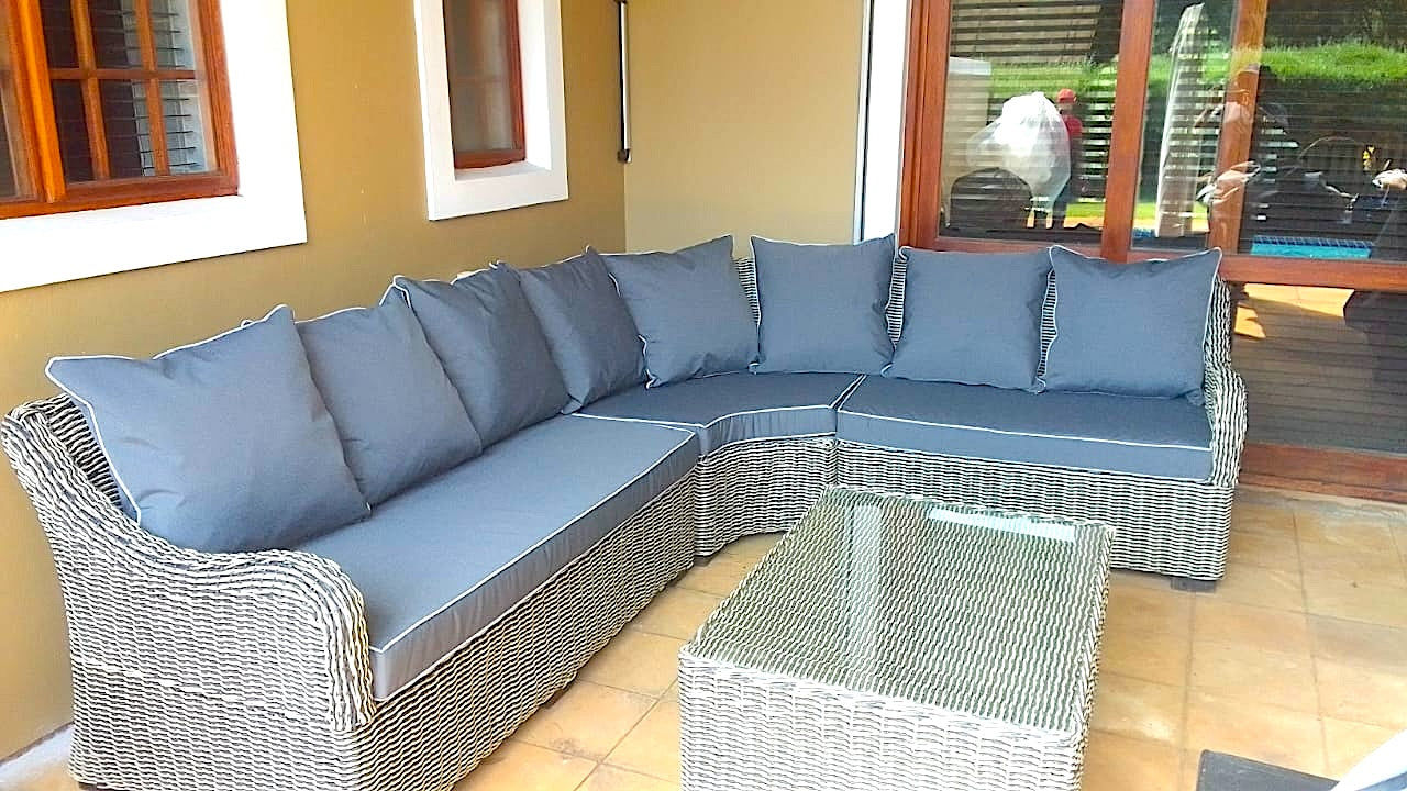 Outdoor patio with wicker sectional sofa and glass coffee table.