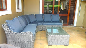 Outdoor patio set with wicker sectional sofa and coffee table on a wooden deck.