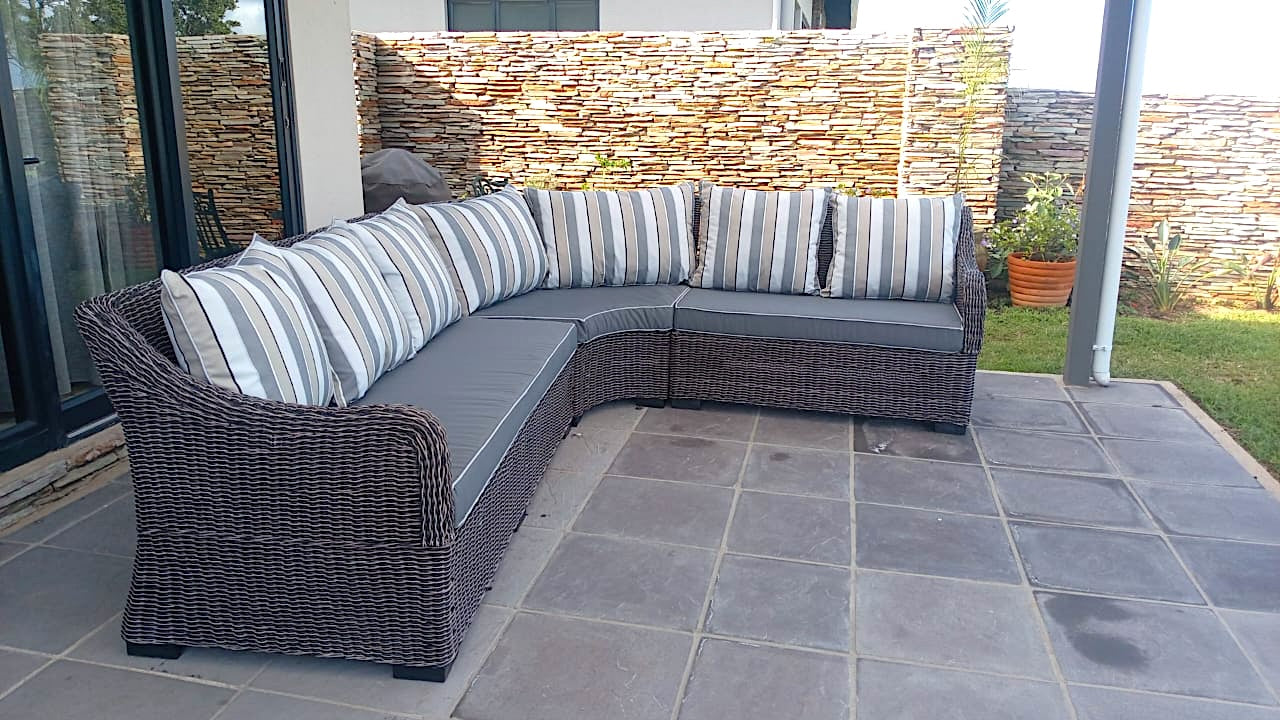 Sectional outdoor sofa with striped cushions on a stone patio.